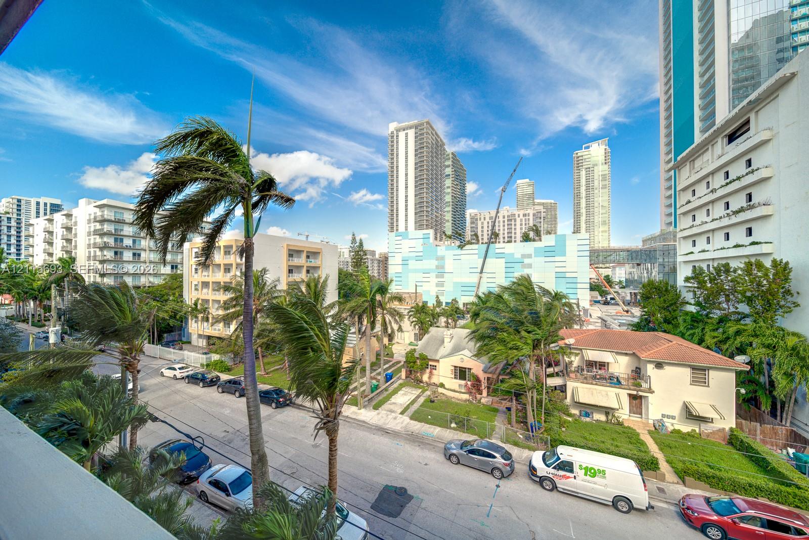 Urban streetscape featuring mature palm trees and mid-rise architecture