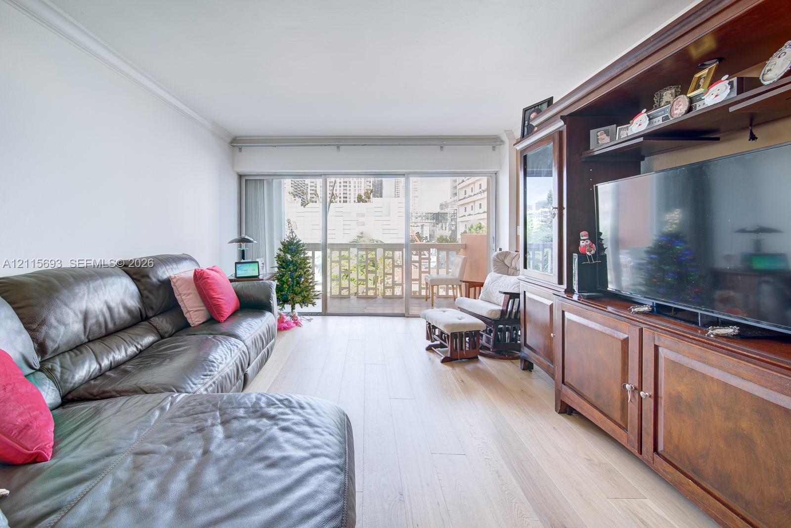 Light-toned wood-finish flooring, floor-to-ceiling sliding glass doors, and a built-in dark wood cabinetry unit