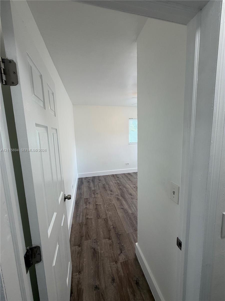 Interior space featuring wood-finish flooring, a multi-panel door, and a recessed window