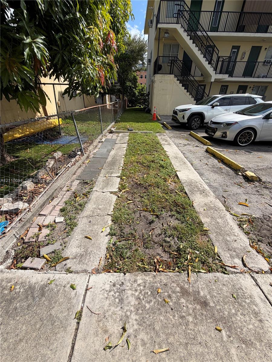 Asphalt parking area featuring concrete tire strips and metal chain-link perimeter fencing