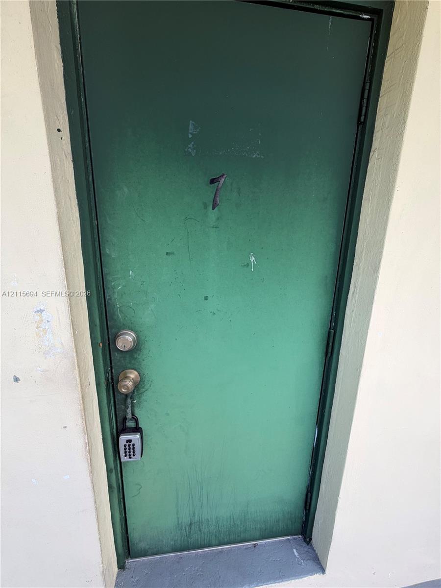 Green painted exterior door featuring a metal frame and a cylindrical knob set
