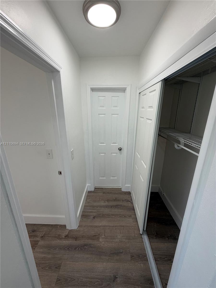 Wood-finish flooring, flush-mount ceiling lighting, four-panel interior door, and reach-in closet featuring sliding doors and built-in wire shelving