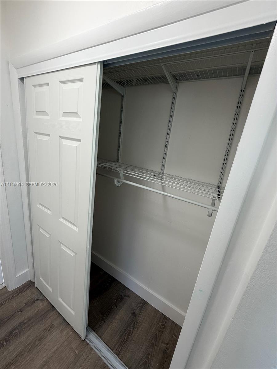Six-panel sliding closet door featuring wire shelving and a built-in hanging rod above wood-finish flooring