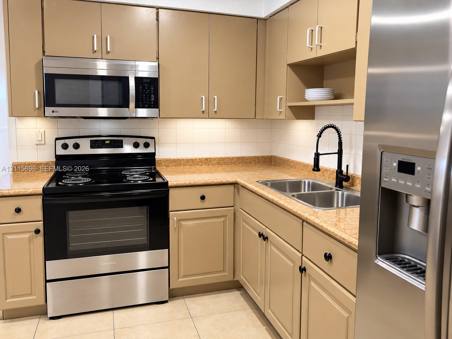 Kitchen featuring stainless steel appliances, neutral cabinetry, stone-finish countertops, ceramic tile backsplash, and a high-arch pull-down faucet