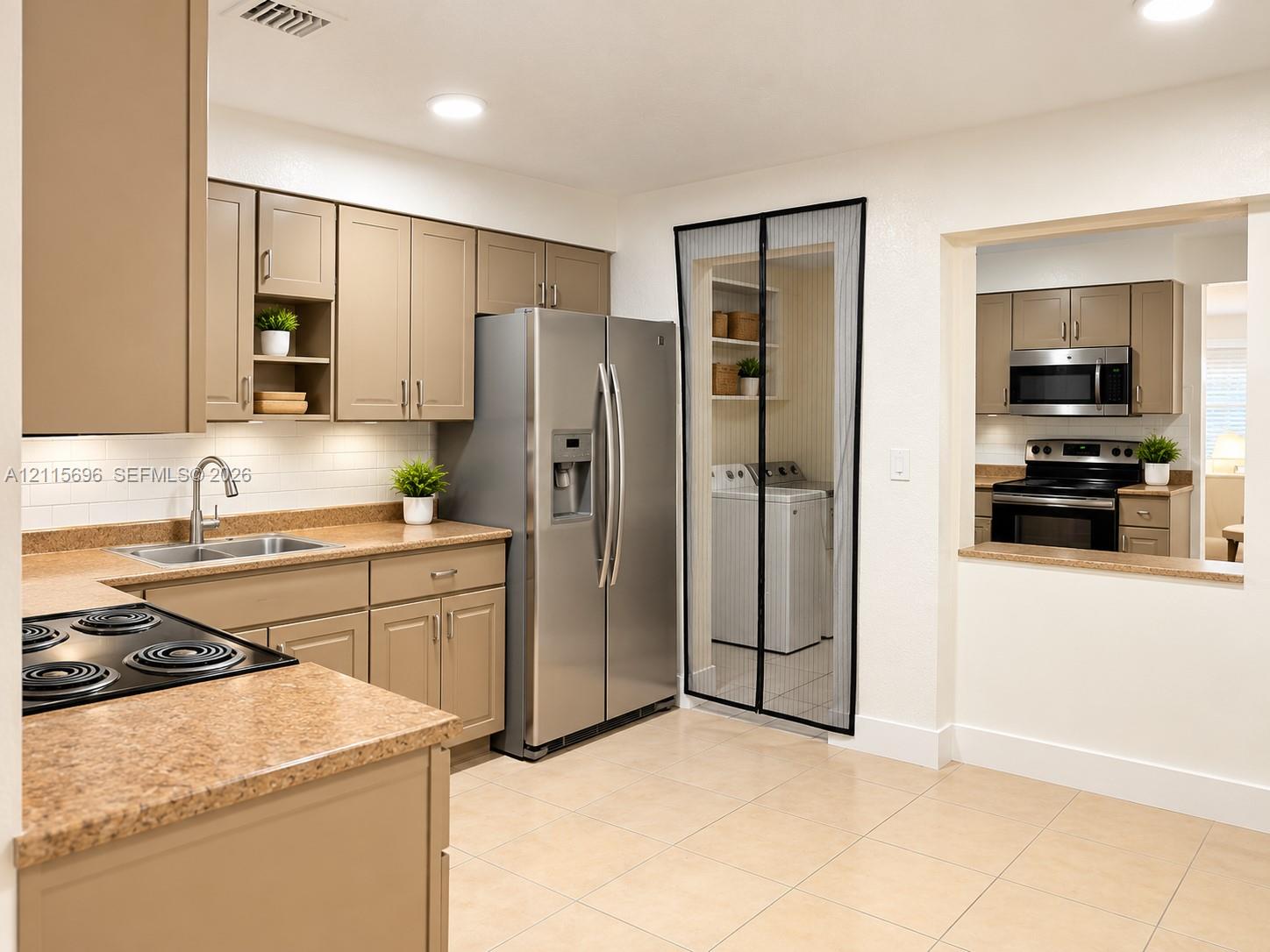 Kitchen featuring flat-panel cabinetry, stone-texture countertops, white subway tile backsplash, stainless steel refrigerator, and recessed lighting