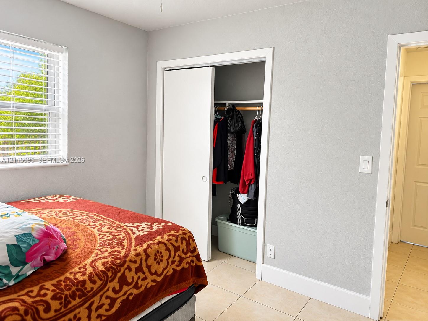 Neutral-toned walls, double-pane sliding window, closet with sliding door, and ceramic tile flooring