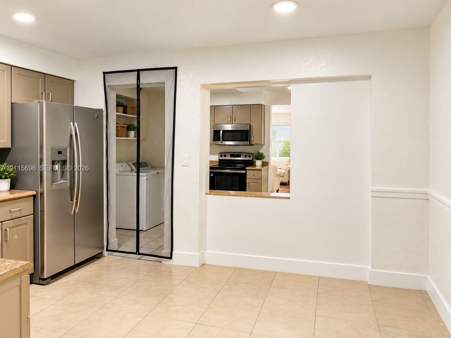 Kitchen featuring tan cabinetry, stainless steel side-by-side refrigerator, recessed lighting, and tile flooring, with a pass-through opening to a cooking area