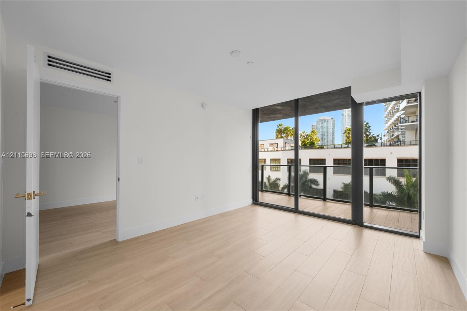 Interior space featuring wood-finish flooring, floor-to-ceiling windows, and a private balcony with a dark metal railing