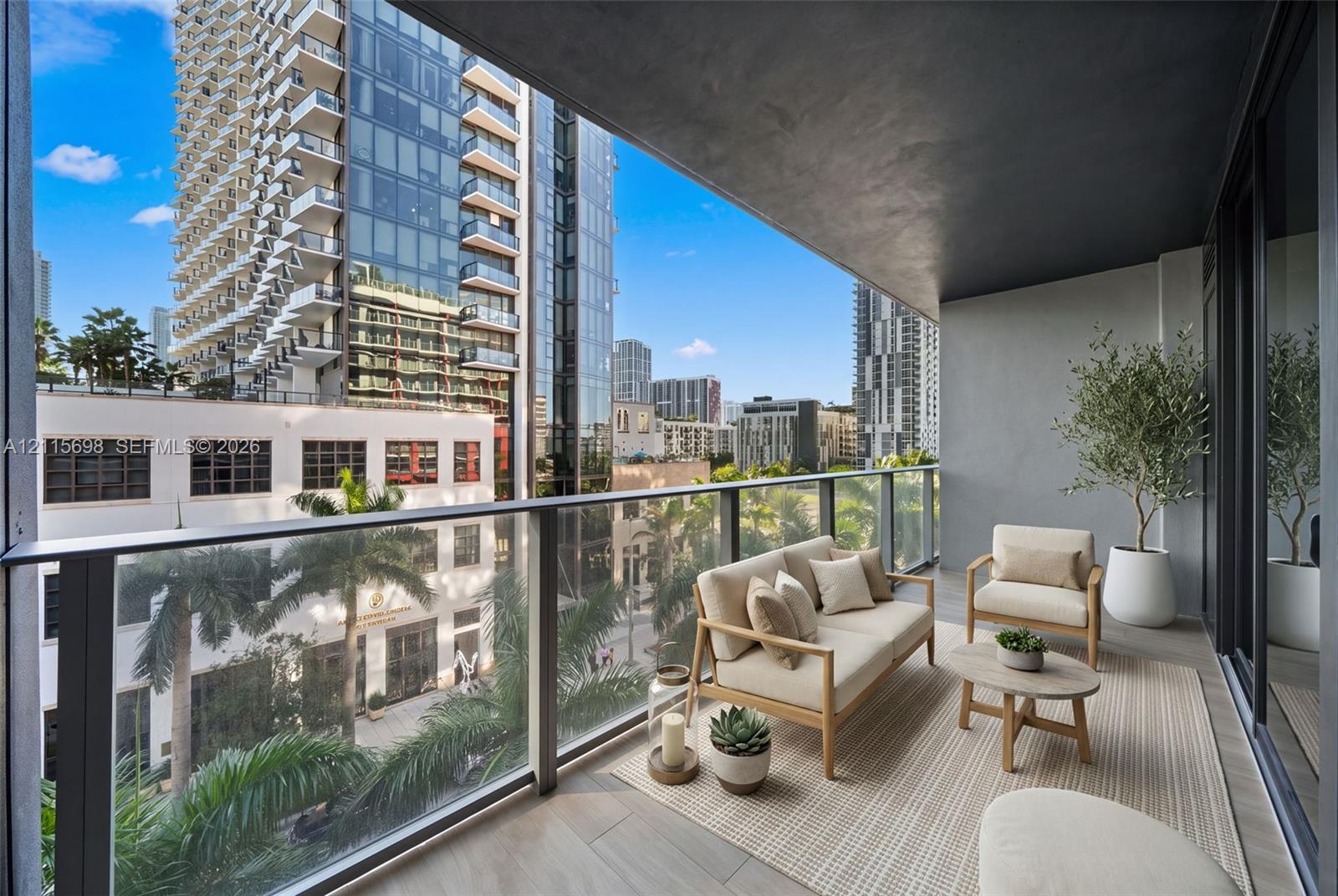 Private covered balcony featuring sleek glass railings, wood-finish flooring, and expansive urban scenery - staged