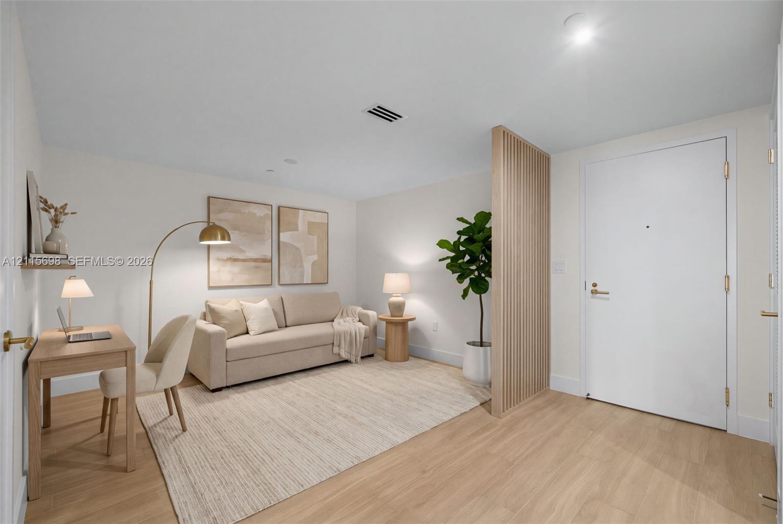 Interior space featuring wood-finish flooring, a decorative vertical slat partition, and a solid-core entry door with gold-toned hardware