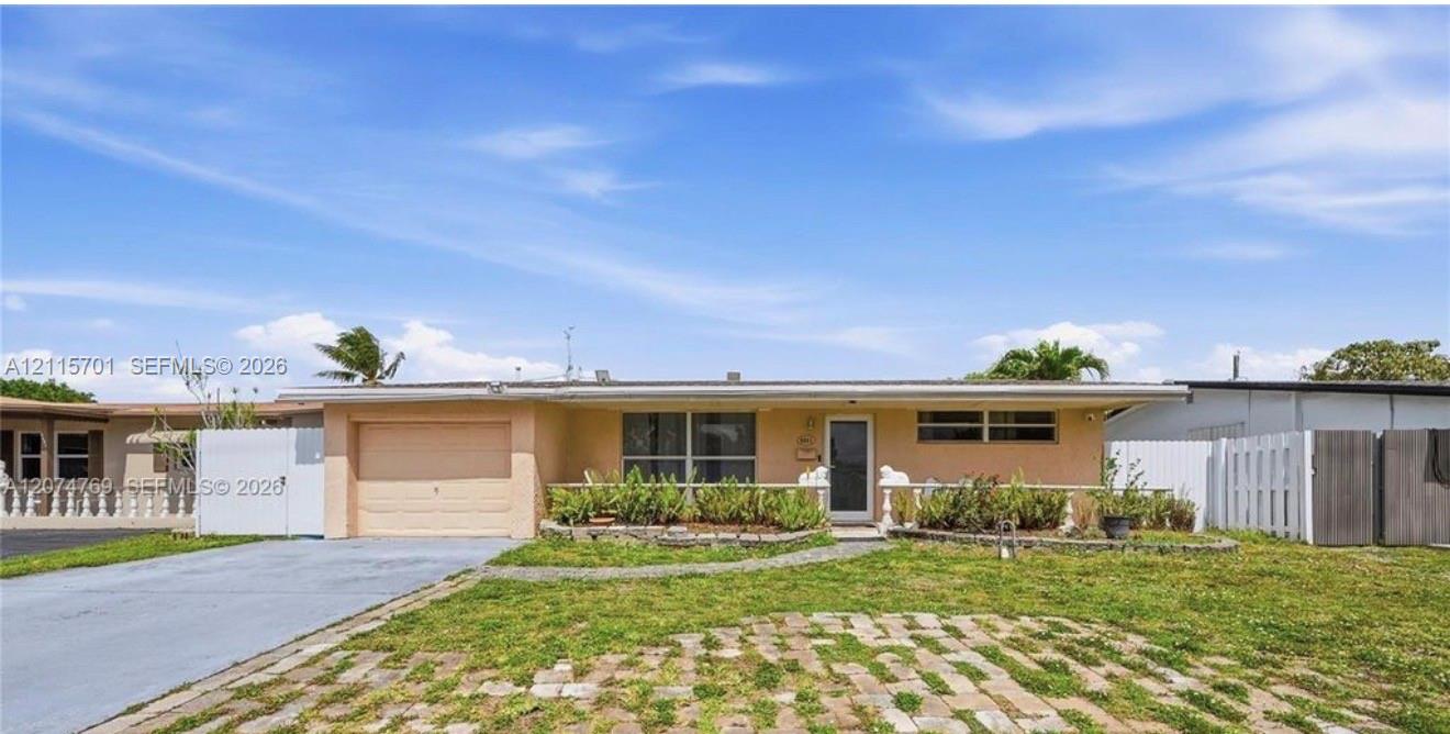 Single-story residence featuring a stucco exterior, attached garage, paved driveway, brick-accented front lawn, and privacy fencing Single-story residence featuring a stucco exterior, attached garage, paved driveway, brick-accented front lawn, and privacy fencing