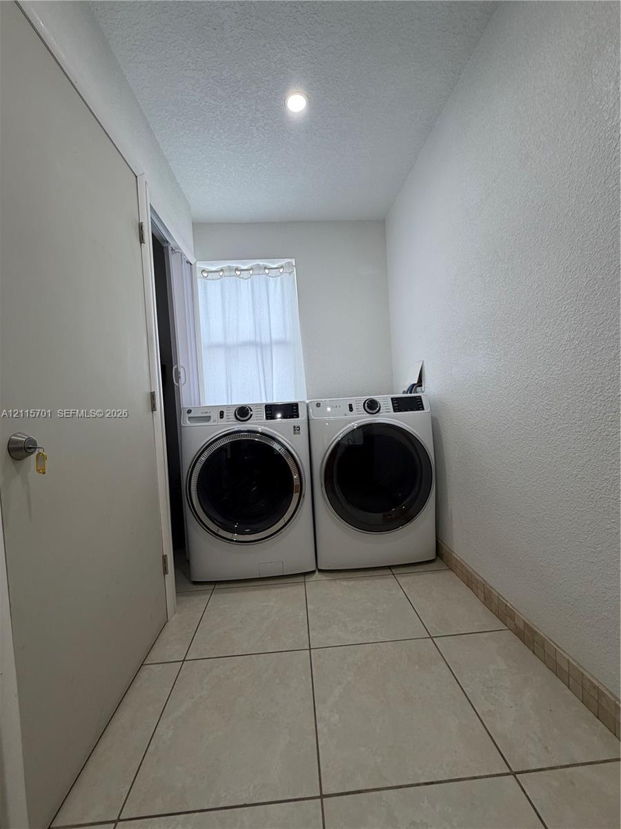 Utility area featuring large-format ceramic tile flooring, neutral wall finishes, and recessed ceiling lighting