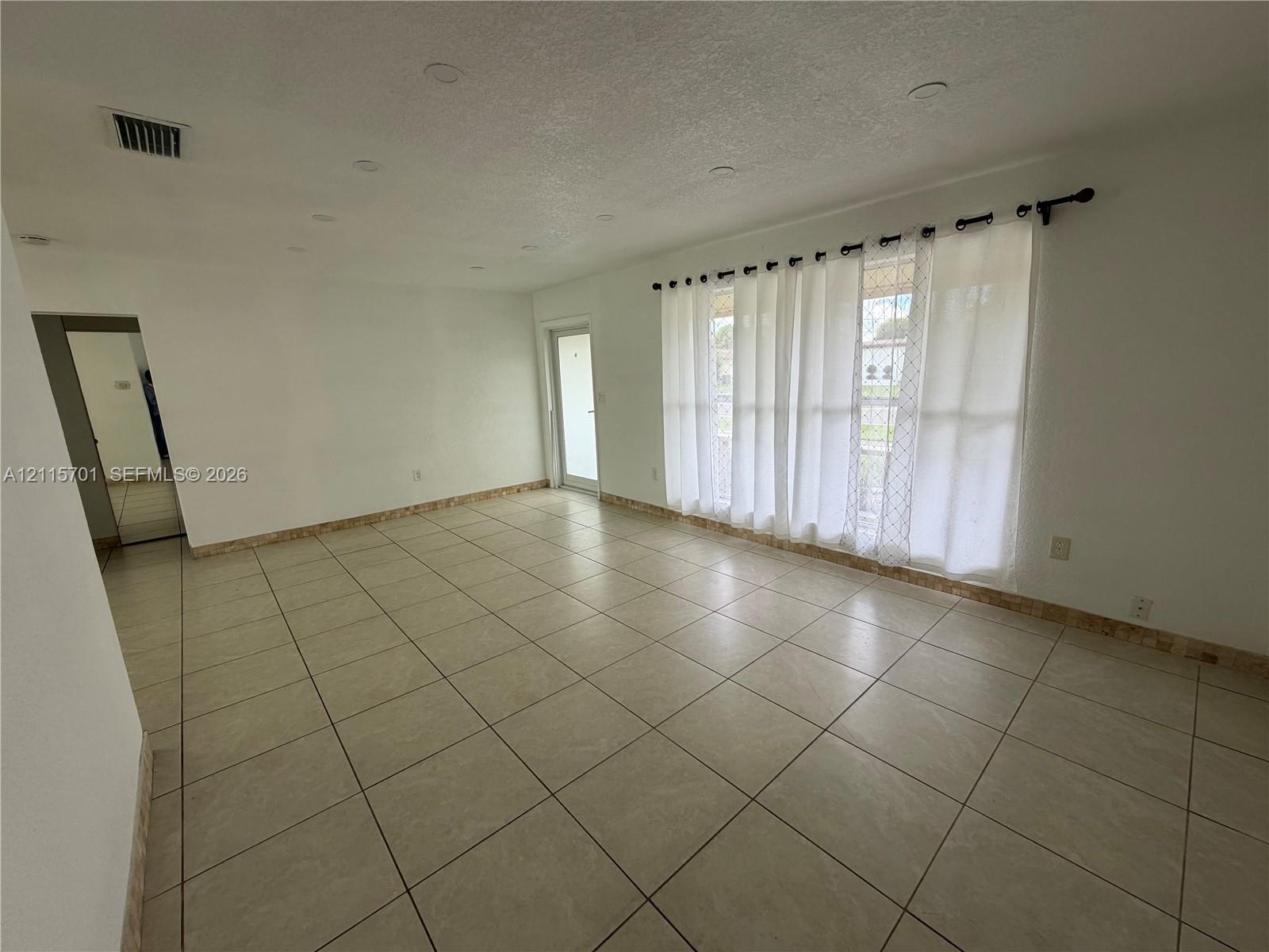 Interior room featuring large-format ceramic tile flooring, recessed lighting, and a glass-paneled exterior door Interior room featuring large-format ceramic tile flooring, recessed lighting, and a glass-paneled exterior door