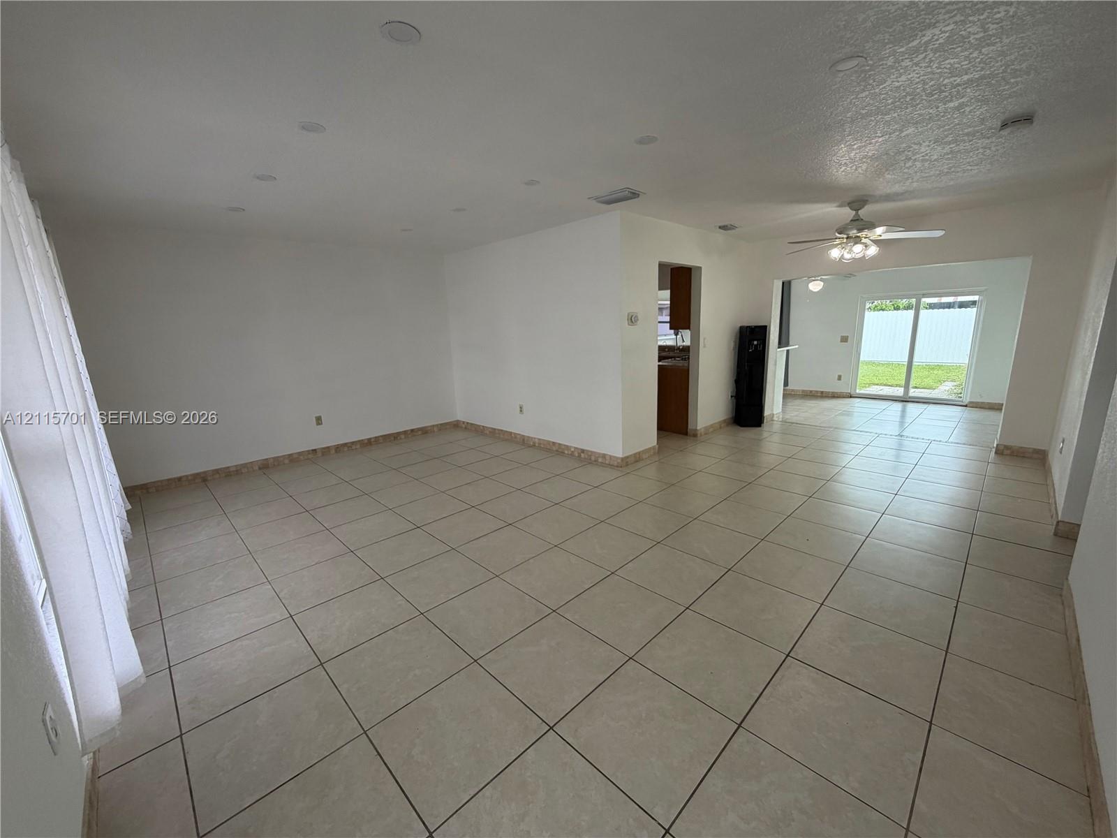 Neutral-toned tile flooring, recessed ceiling lighting, ceiling fan, and sliding glass door Neutral-toned tile flooring, recessed ceiling lighting, ceiling fan, and sliding glass door