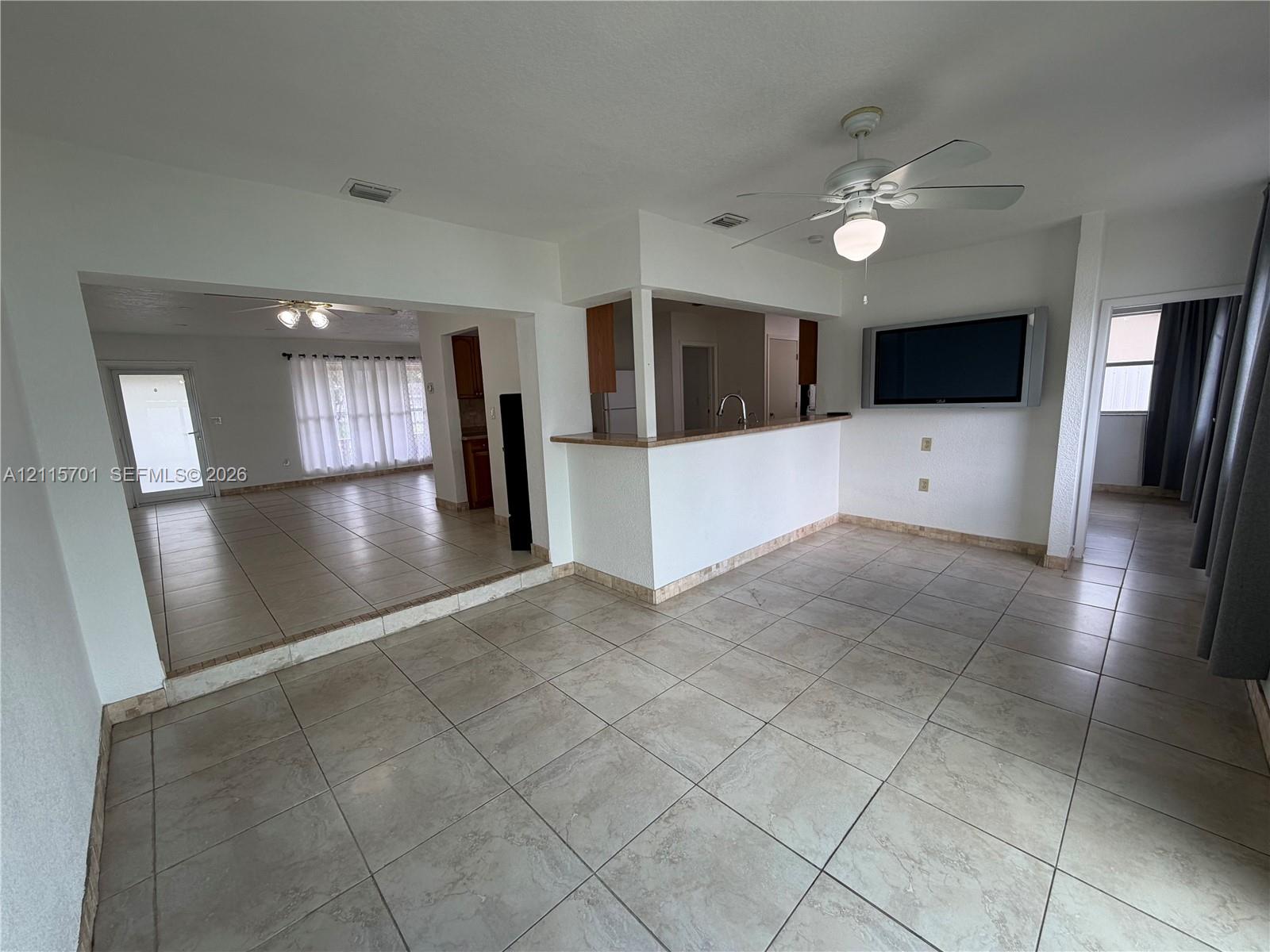 Neutral-toned ceramic tile flooring, kitchen pass-through counter, and ceiling-mounted lighting fixtures Neutral-toned ceramic tile flooring, kitchen pass-through counter, and ceiling-mounted lighting fixtures