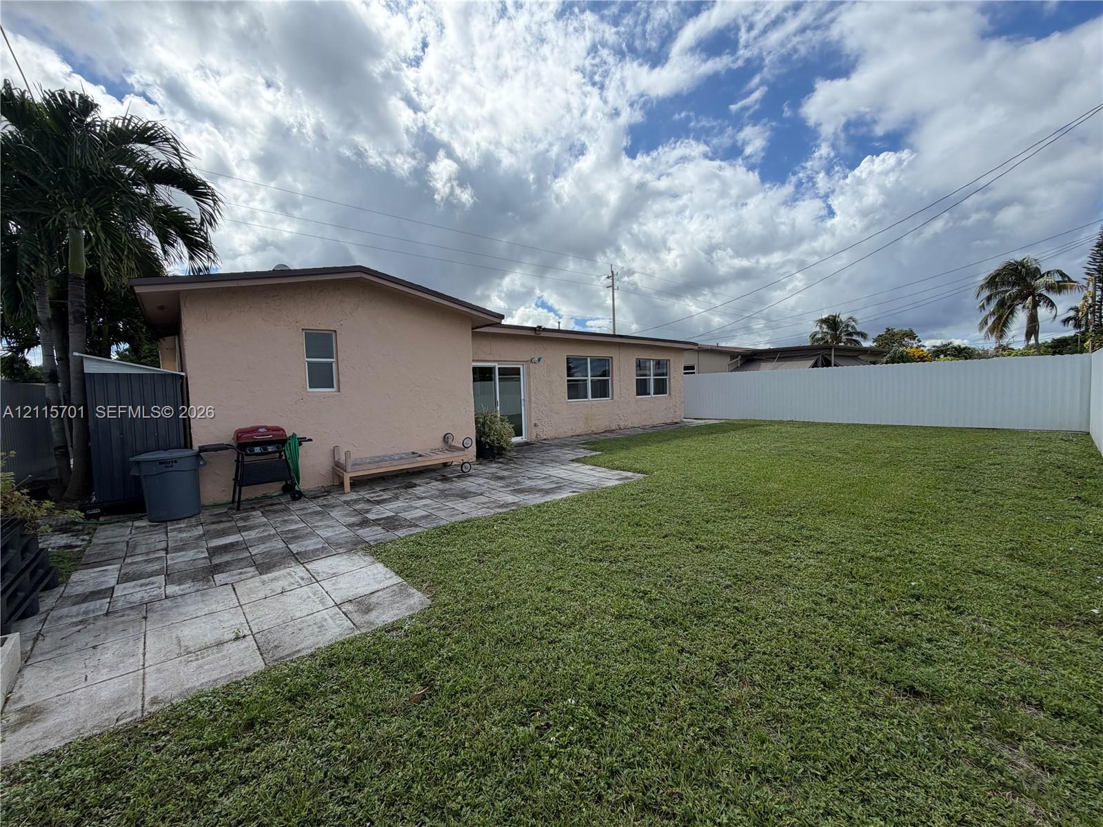 Stucco exterior with a rear paver patio, expansive grass lawn, and full-perimeter privacy fencing