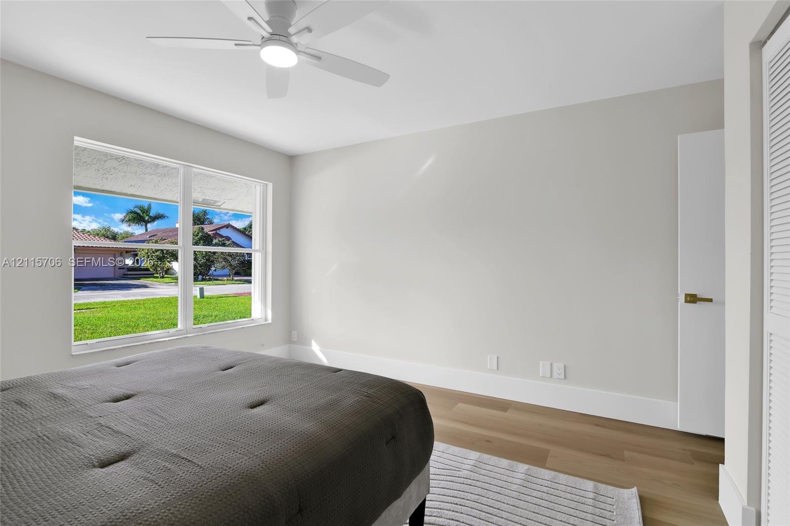 Neutral wall palette, wood-finish flooring, ceiling fan with integrated lighting, and multi-pane window