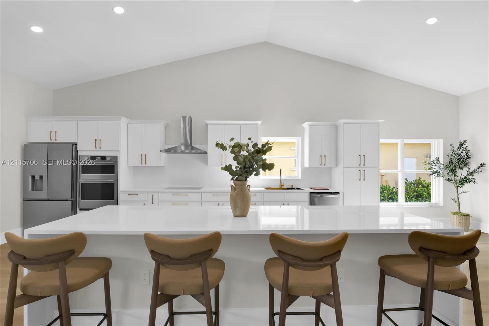 Vaulted ceilings, large kitchen island with a white solid-surface countertop, white shaker-style cabinetry, stainless steel double wall oven, and a chimney-style range hood