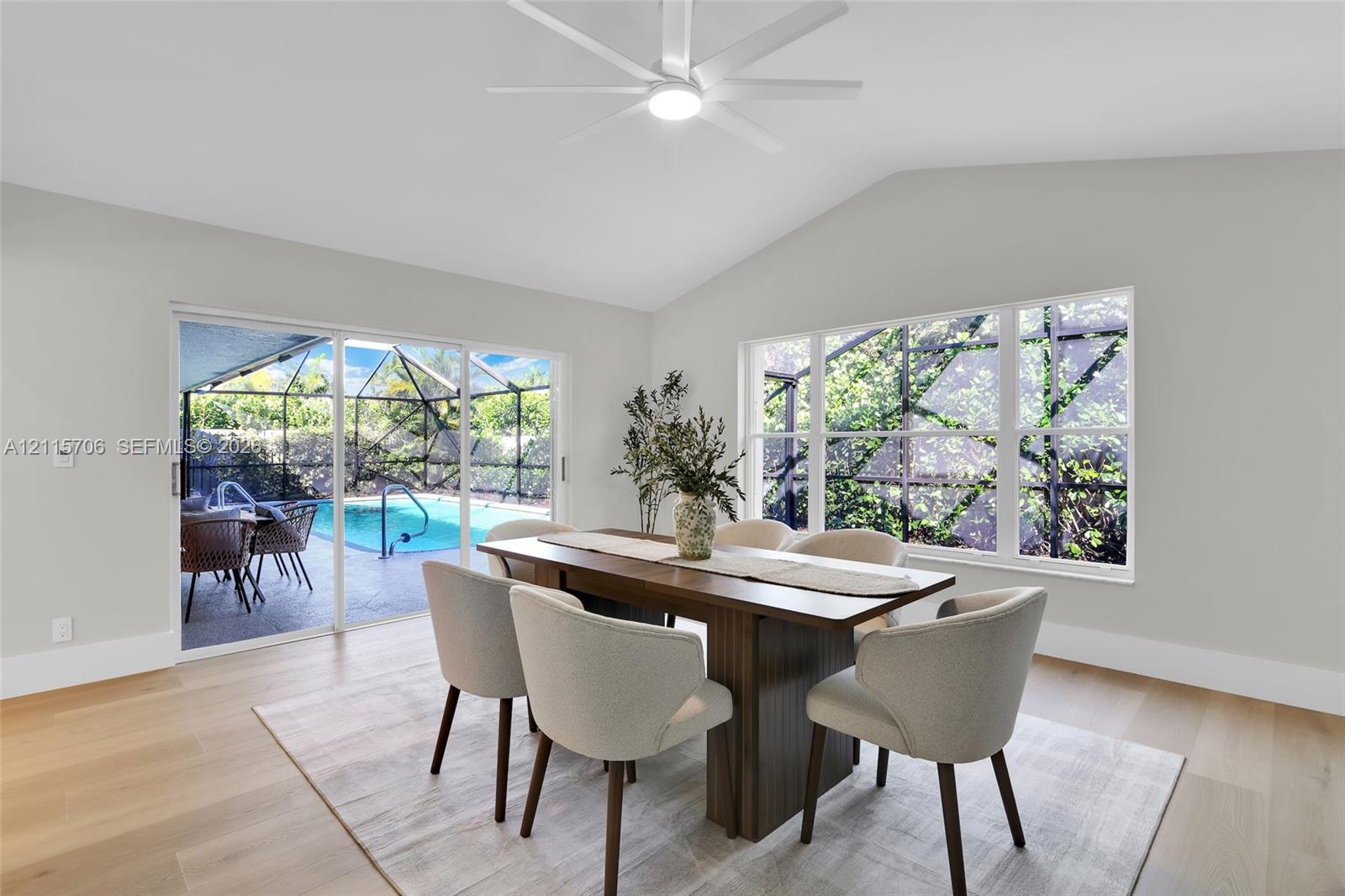Vaulted ceilings, wood-finish flooring, recessed LED ceiling fan, and sliding glass doors with direct exterior access