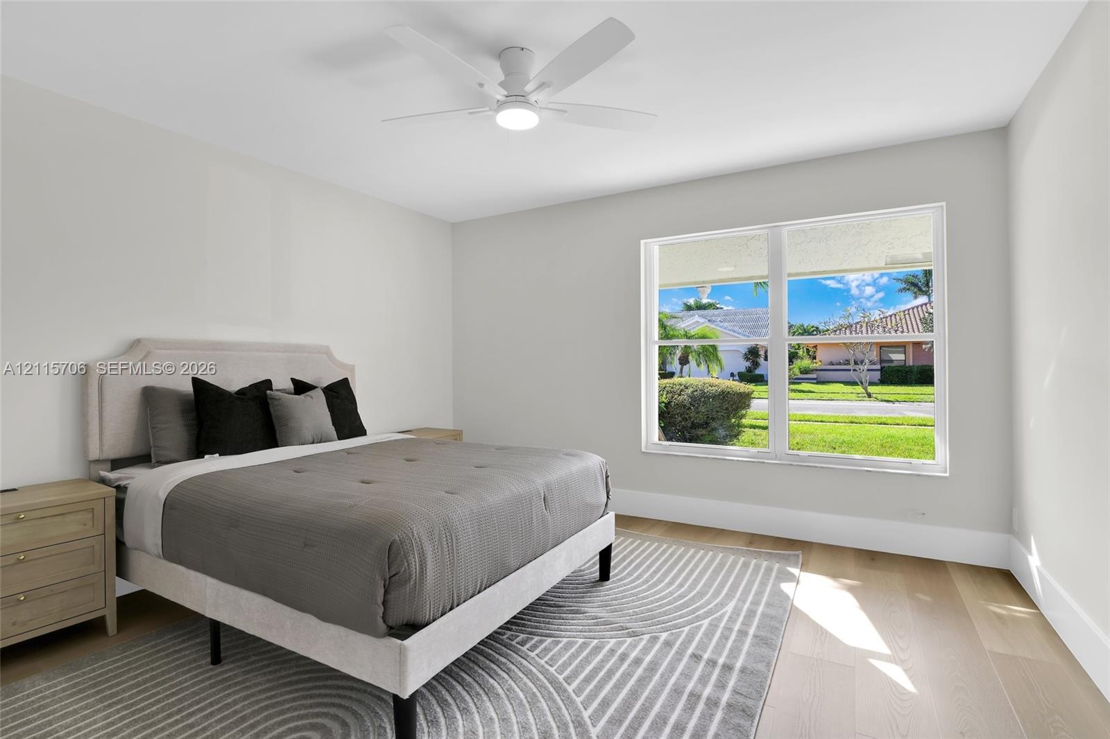 Neutral wall palette featuring wood-finish flooring, a large picture window, and a central ceiling fan with integrated lighting