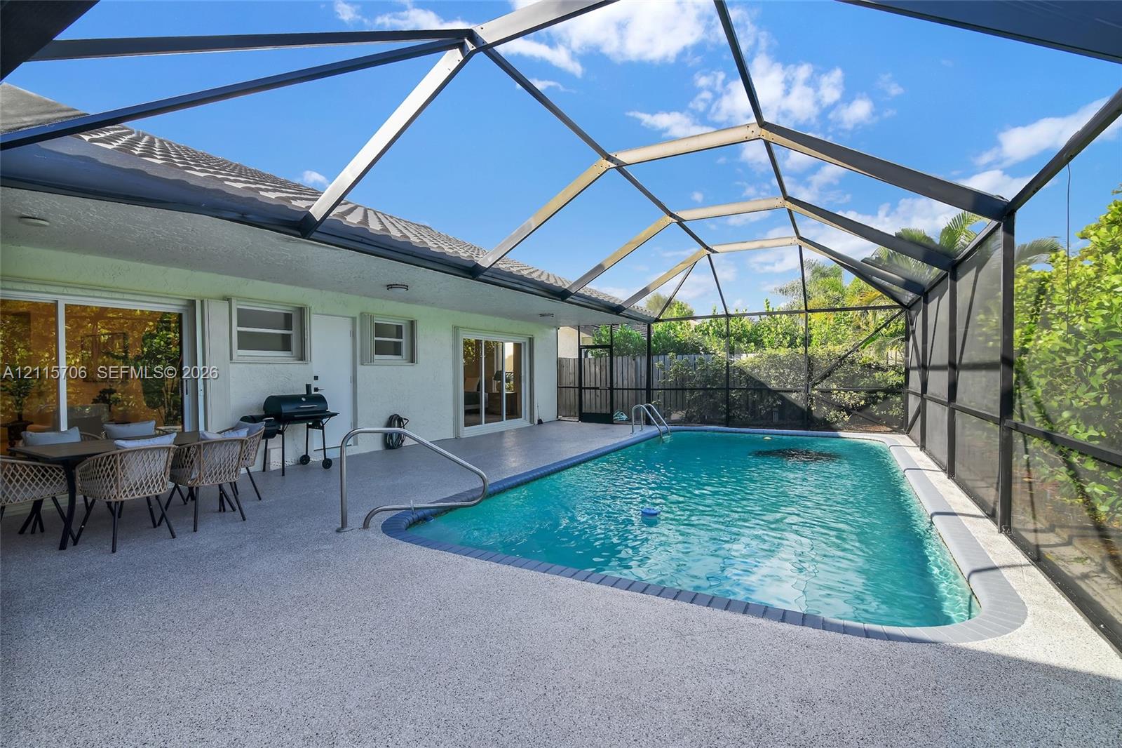 Enclosed swimming pool with a concrete pool deck, screened-in lanai, and sliding glass door access to the residence