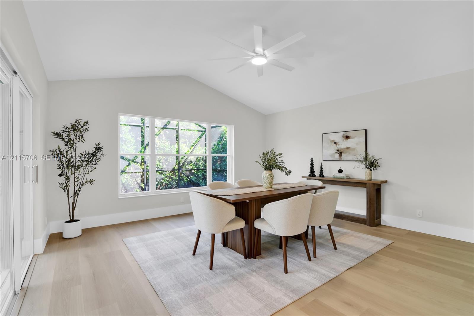 Vaulted ceilings, wood-finish flooring, multi-pane window, and white ceiling fan with integrated lighting