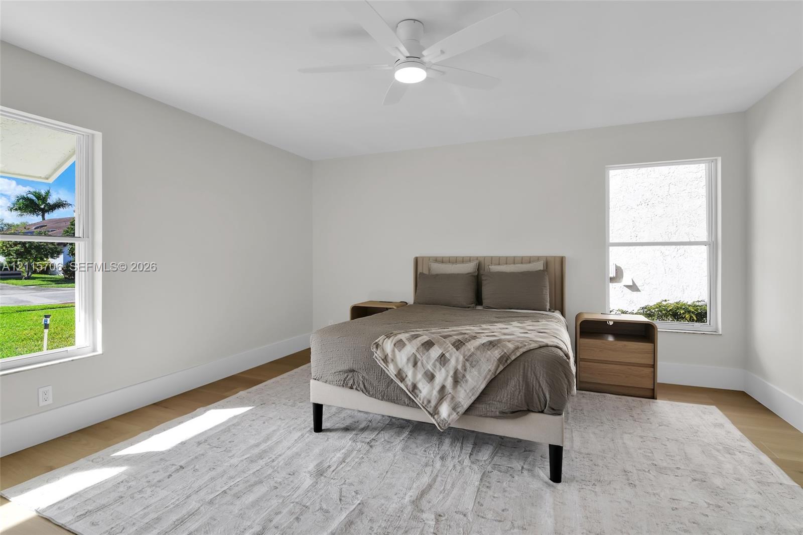 Neutral-toned walls paired with wood-finish flooring, dual windows, and a central ceiling fan with integrated lighting