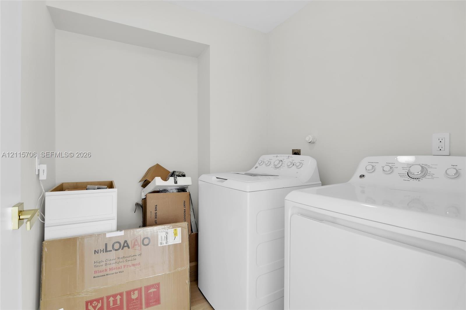 Dedicated laundry area featuring a white top-load washer, white electric dryer, and gold-finish door hardware