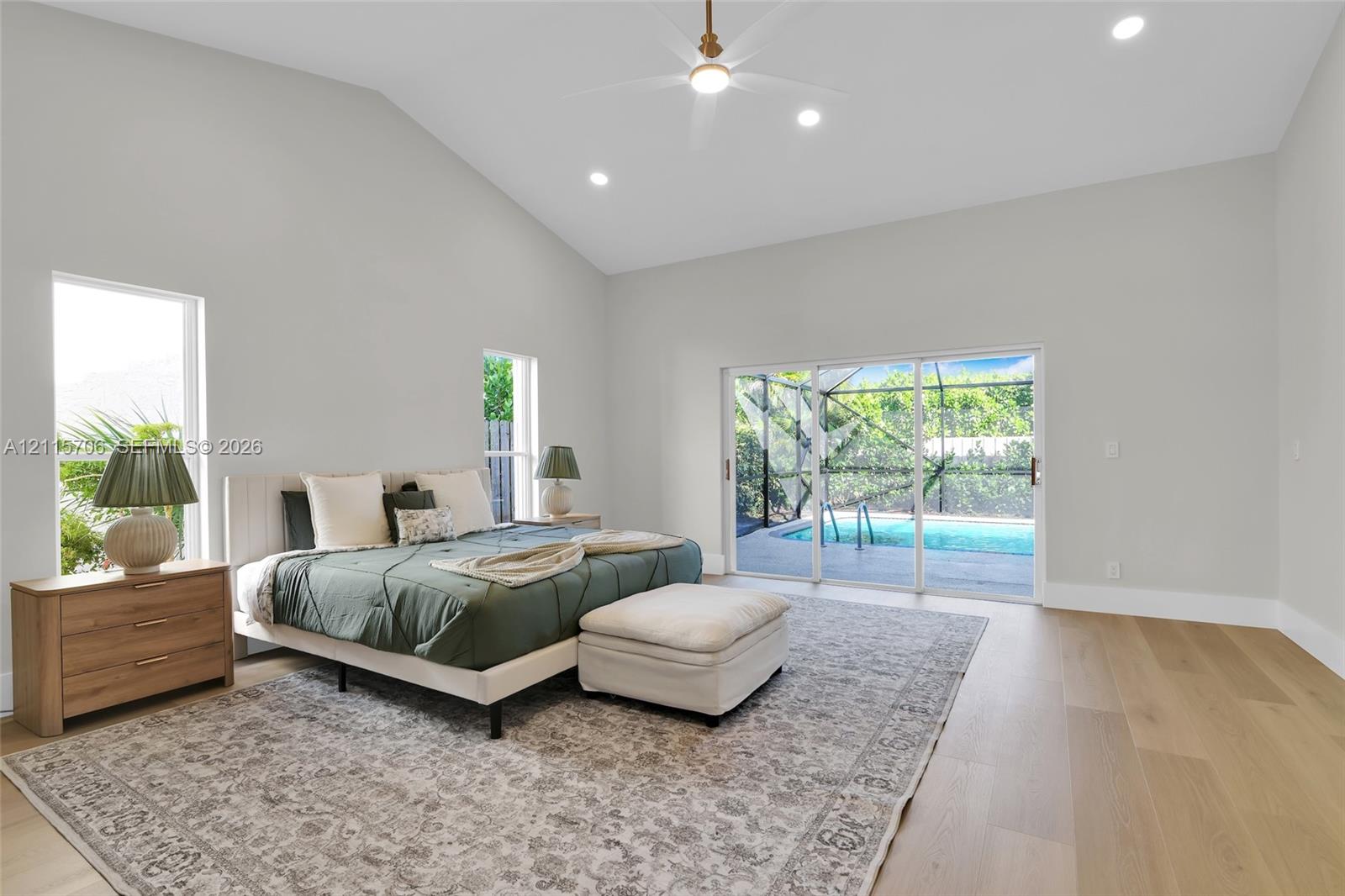 Vaulted ceilings, wood-finish flooring, recessed lighting, ceiling fan, and sliding glass doors with direct access to a screened-in pool area