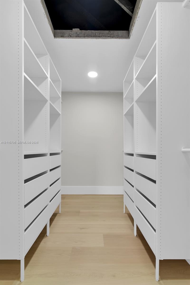 Custom white built-in cabinetry featuring adjustable open shelving, integrated drawers, and wood-finish flooring