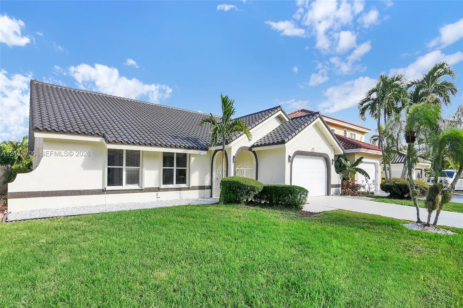 Single-story residence featuring a tile roof, stucco exterior, arched entryway, and attached garage