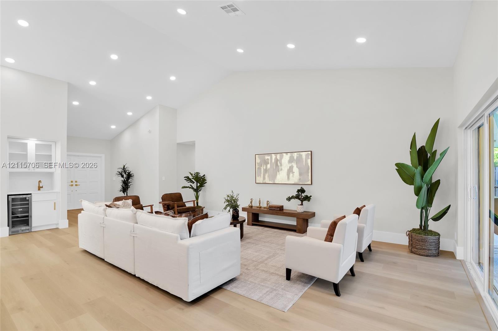 Vaulted ceilings, wood-finish flooring, recessed lighting, and a built-in wet bar with glass-front cabinetry and integrated wine storage