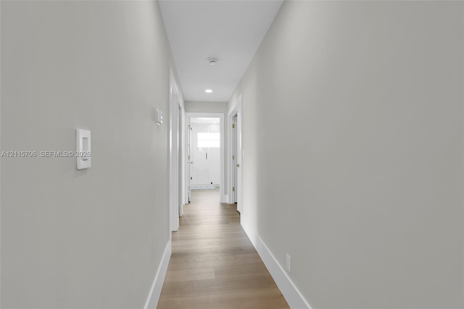 Hallway featuring neutral wall tones, wood-finish flooring, and recessed ceiling lighting