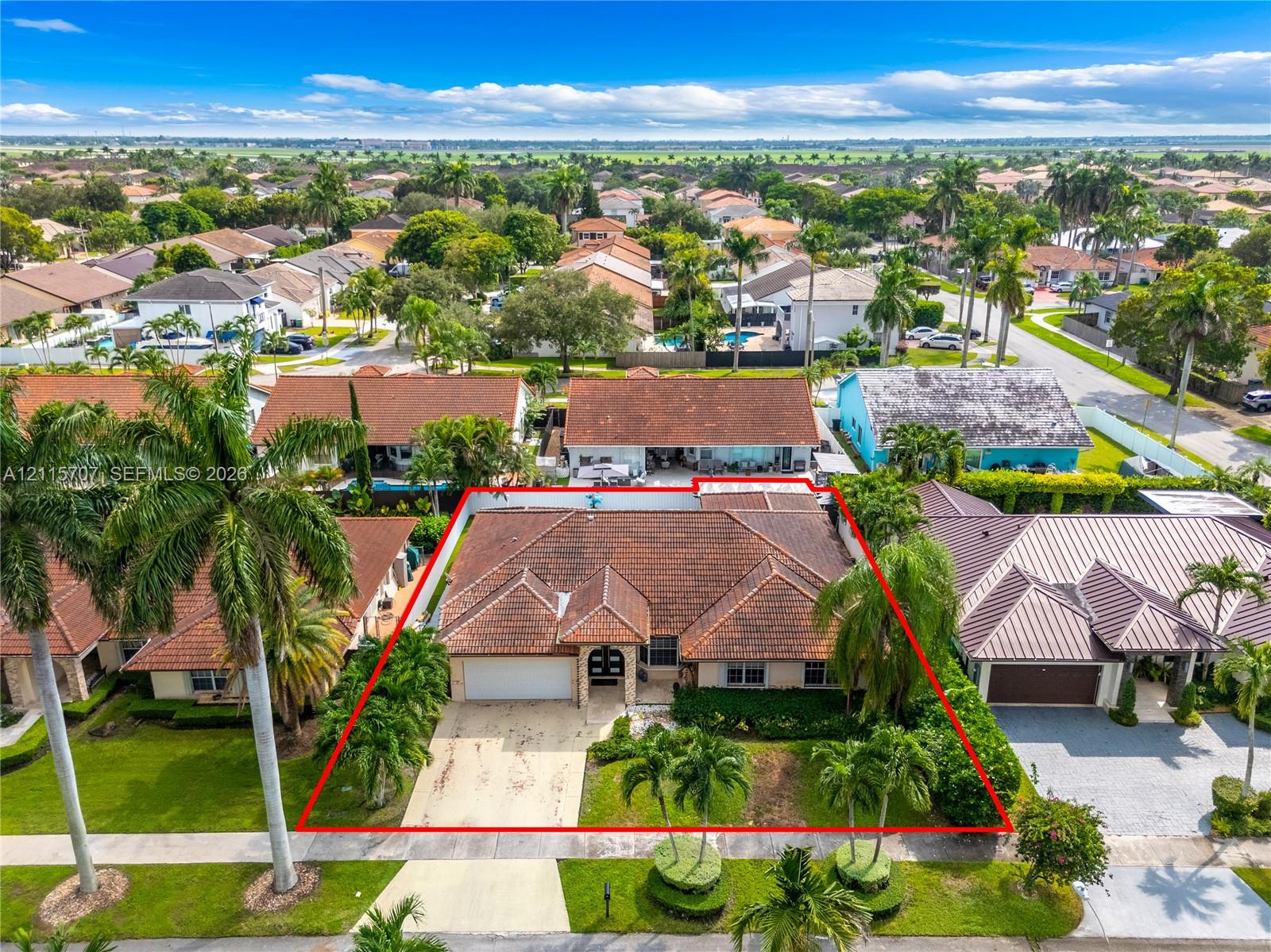 Single-story residence featuring a tile roof, stucco exterior, two-car garage, and established landscaping with palm trees