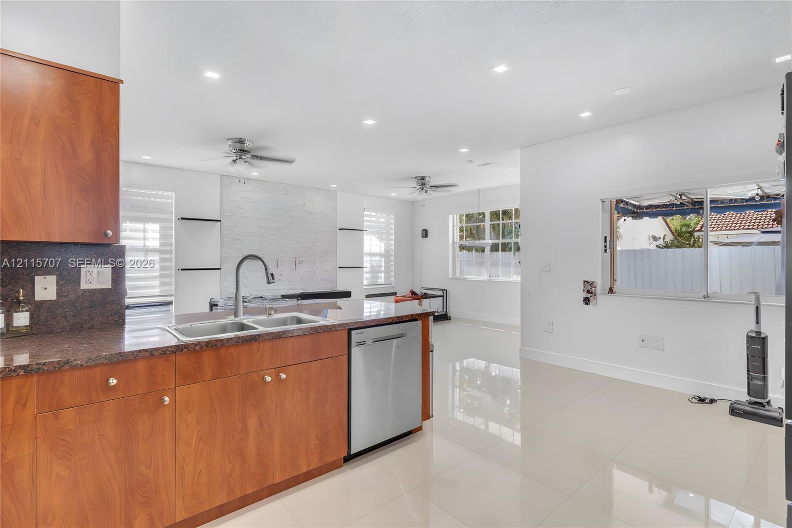 Kitchen featuring wood-finish cabinetry, stone-surface countertops, stainless steel dishwasher, recessed lighting, and tile flooring