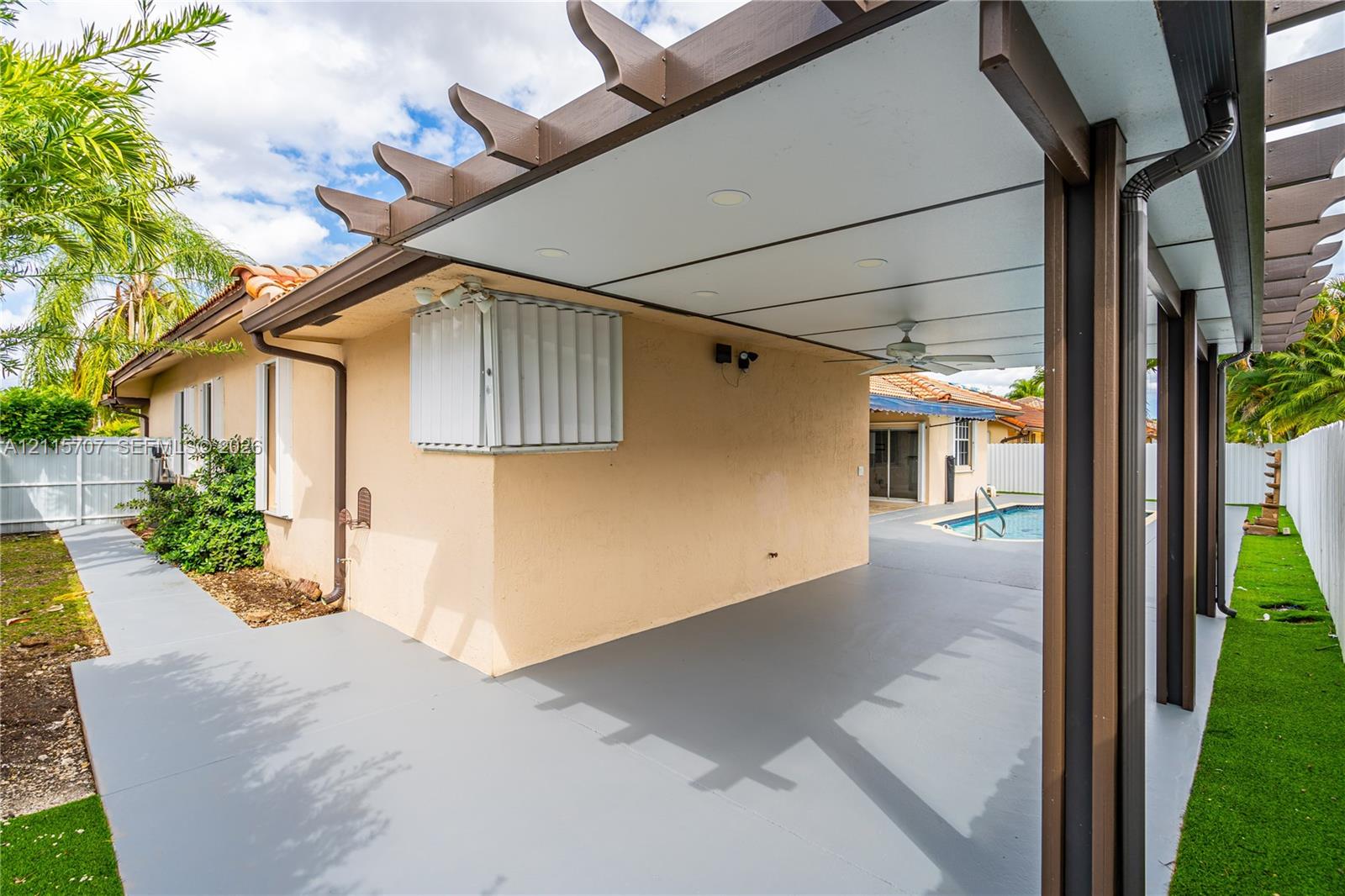Covered outdoor patio featuring a pergola-style roof structure, recessed lighting, ceiling fan, and painted concrete flooring