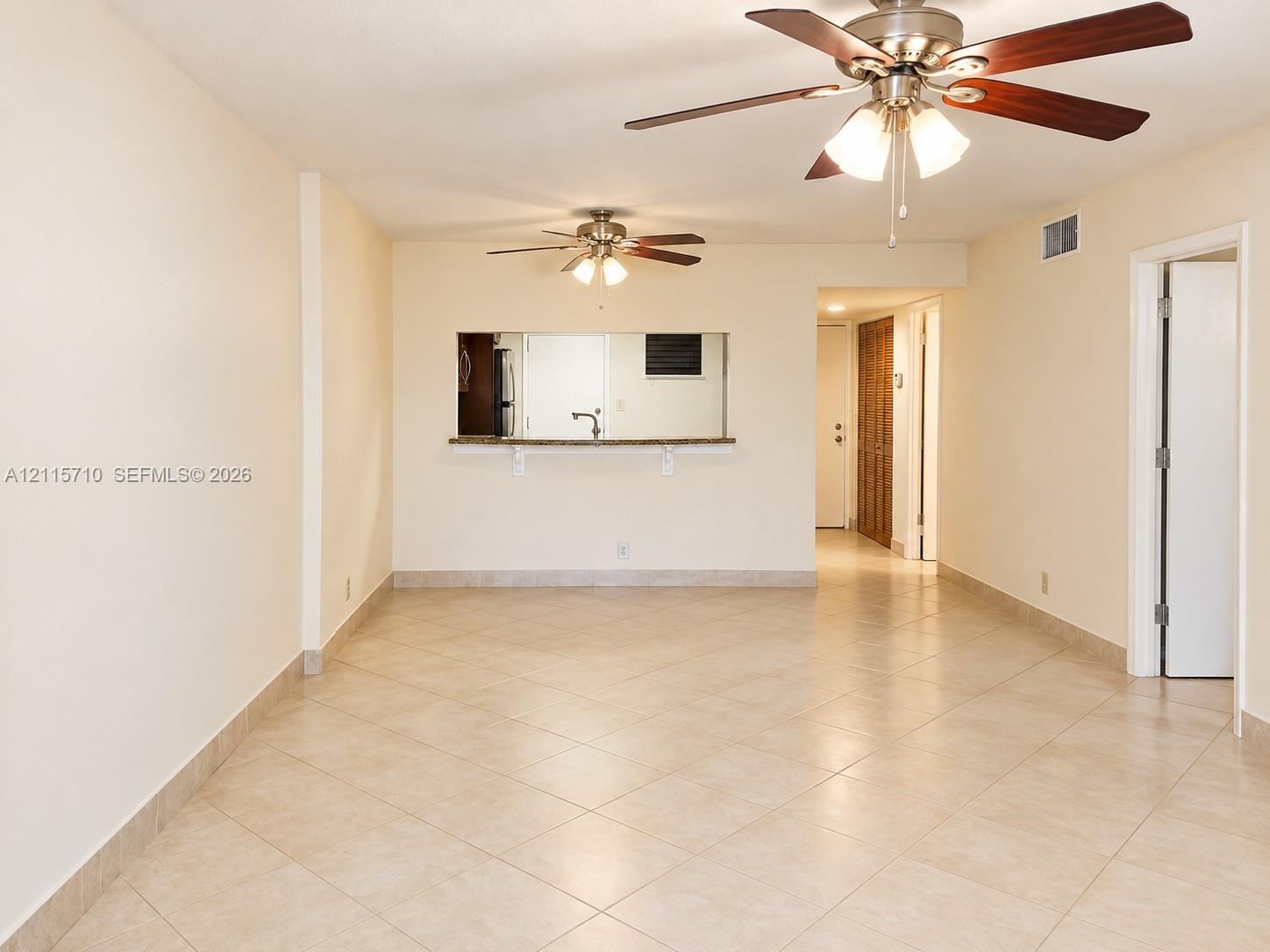 Neutral ceramic tile flooring, dual ceiling fans with integrated lighting fixtures, and a stone-surface pass-through window with an attached service counter