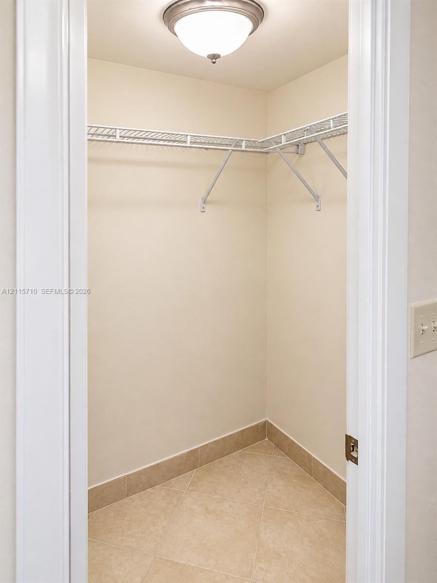 Storage area featuring ceramic tile flooring, built-in wire shelving, and a ceiling-mounted light fixture