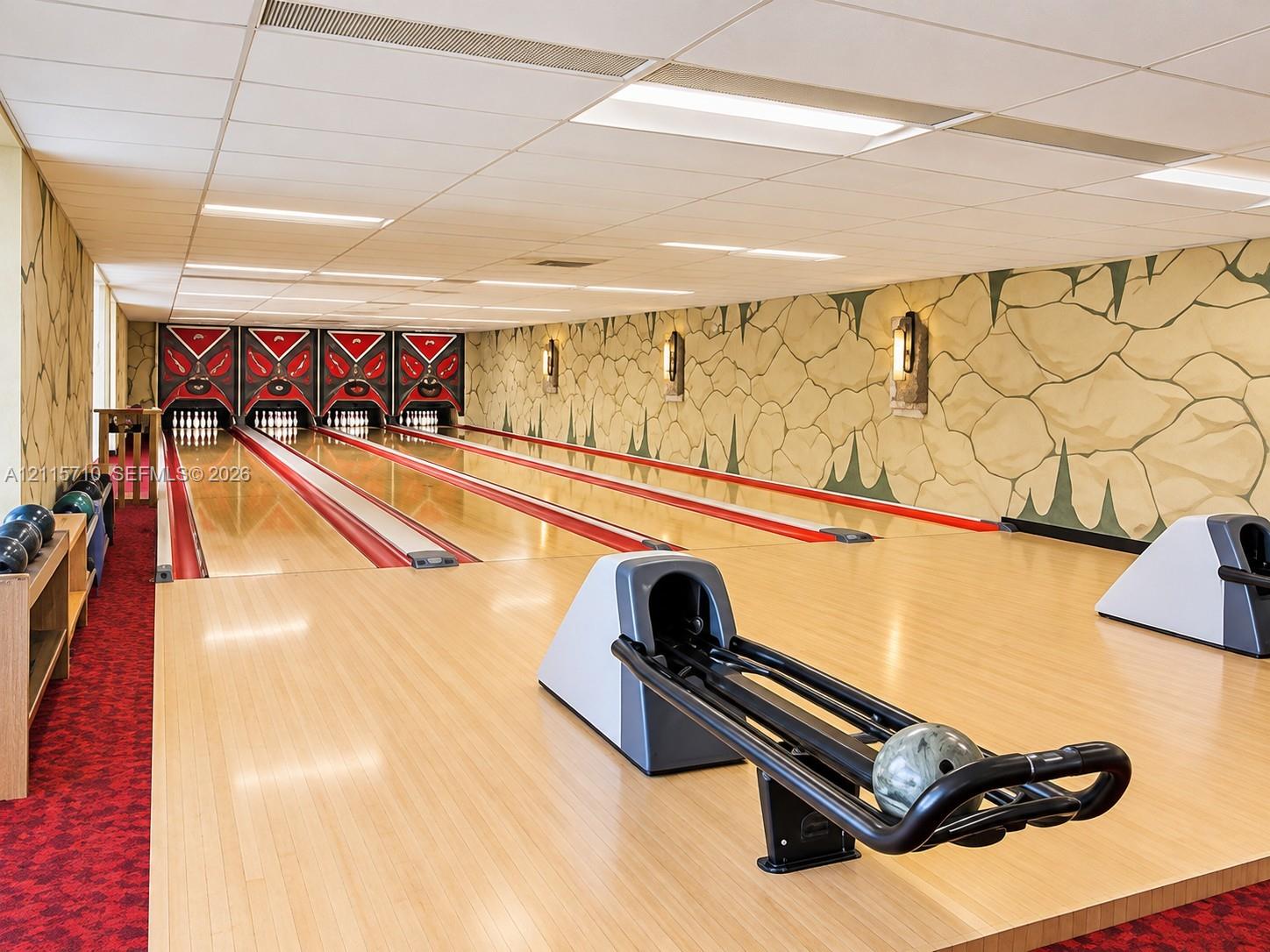 Private multi-lane bowling alley featuring polished hardwood lanes, ball returns, pinsetters, and decorative wall murals