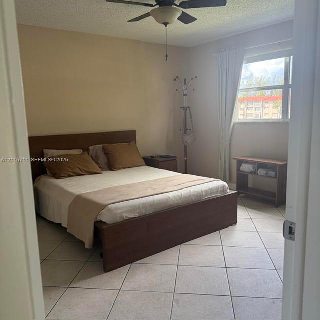 Neutral-toned room featuring large-format ceramic tile flooring, a multi-blade ceiling fan, and a single-pane window