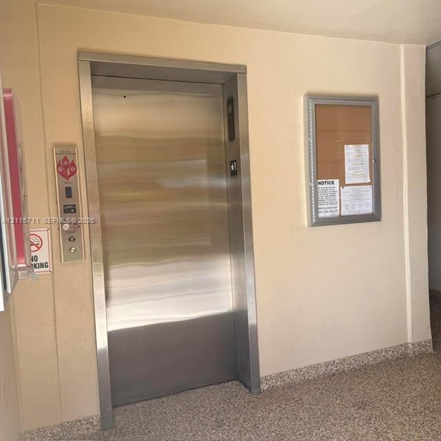 Elevator featuring brushed stainless steel doors and a metallic frame with a wall-mounted call panel