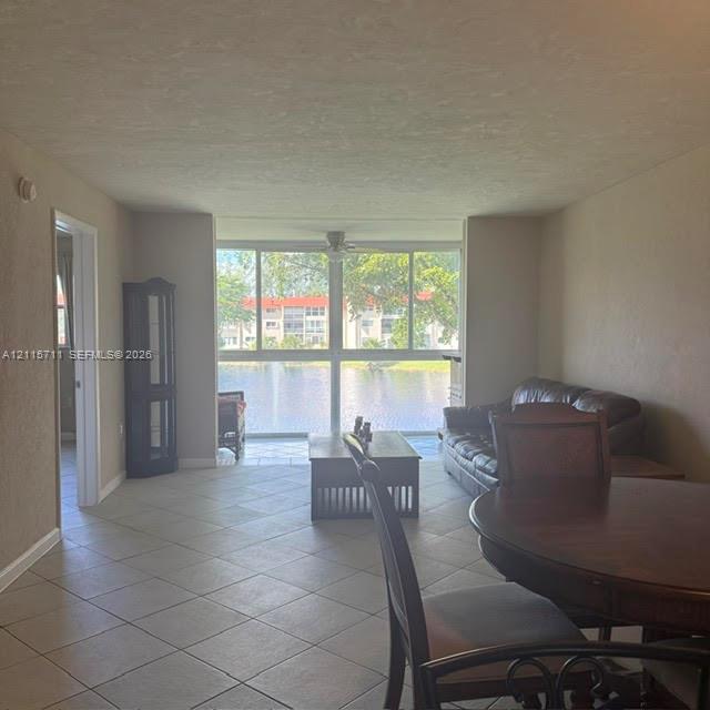 Living space featuring neutral ceramic tile flooring and floor-to-ceiling windows with water frontage