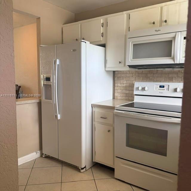 Kitchen featuring white cabinetry, subway tile backsplash, white appliances, and tile flooring