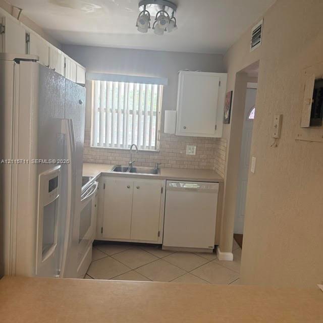 Kitchen featuring white cabinetry, a tiled backsplash, a double-basin stainless steel sink, and ceramic tile flooring