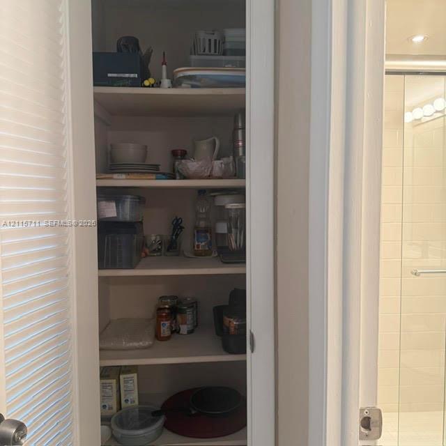 Built-in storage pantry featuring white louvered doors and five fixed shelves