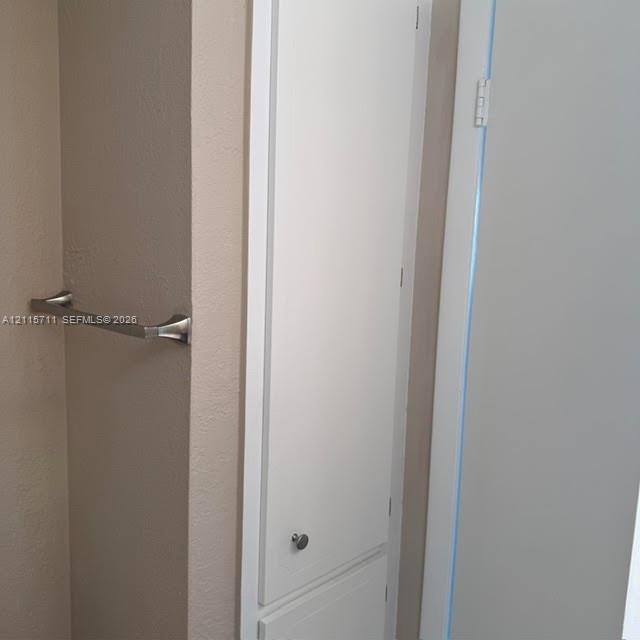 Built-in floor-to-ceiling white cabinetry featuring a brushed metal knob and a matching brushed metal horizontal towel bar