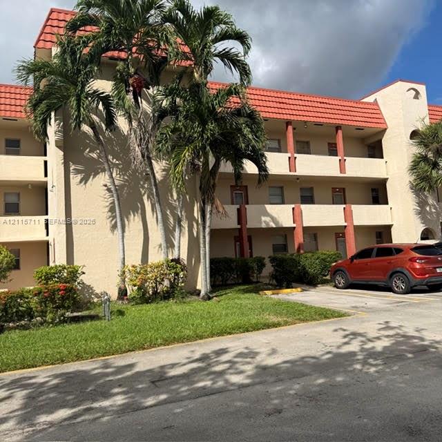 Multi-story stucco exterior featuring a red tile roof and covered balcony access