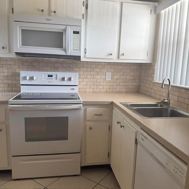 Kitchen featuring white cabinetry, an integrated microwave, a slide-in range, a stainless steel double-basin sink with a gooseneck faucet, and a stone-style tile backsplash