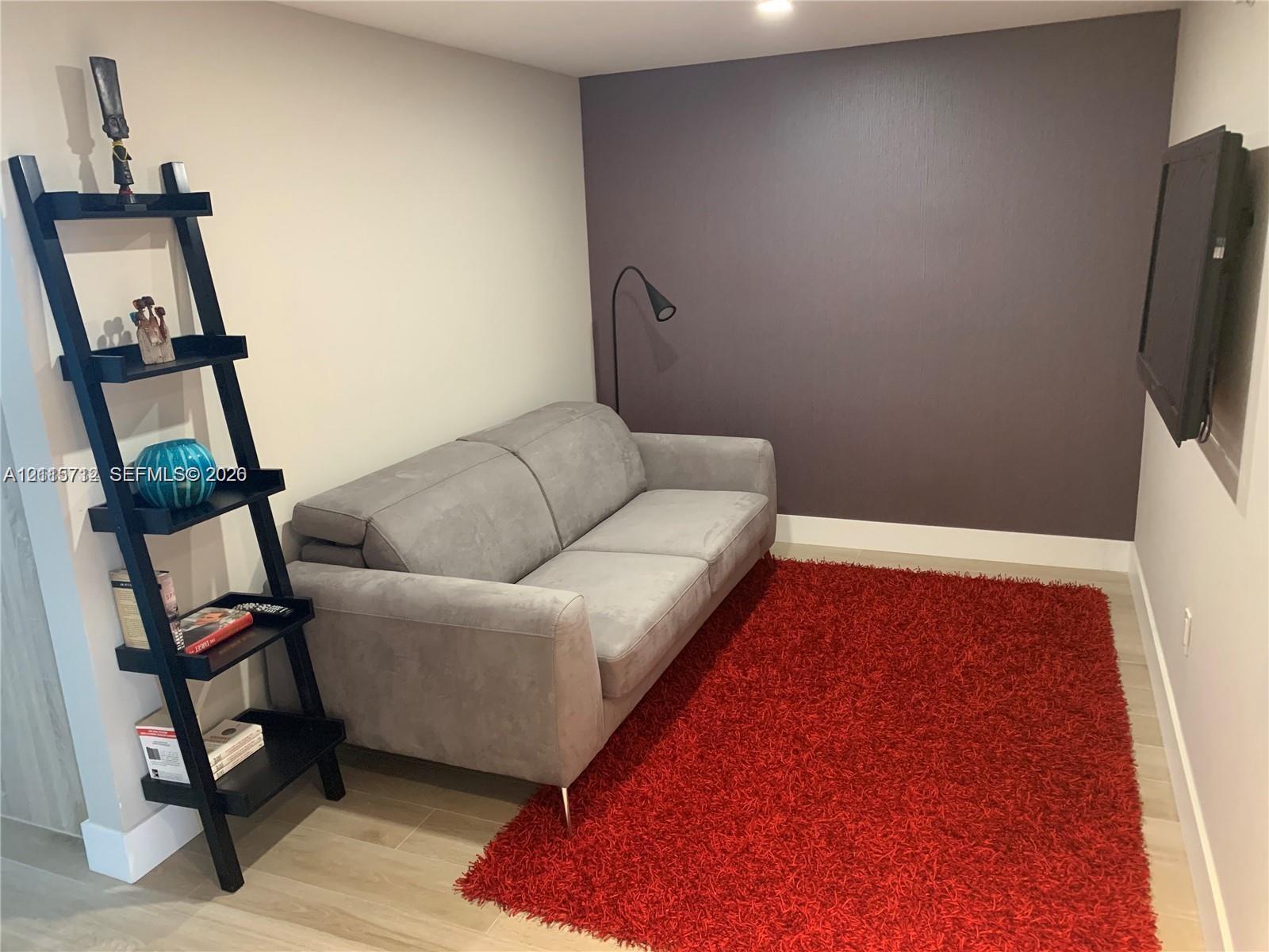 Room featuring wood-finish flooring, a charcoal-toned accent wall, and recessed ceiling lighting