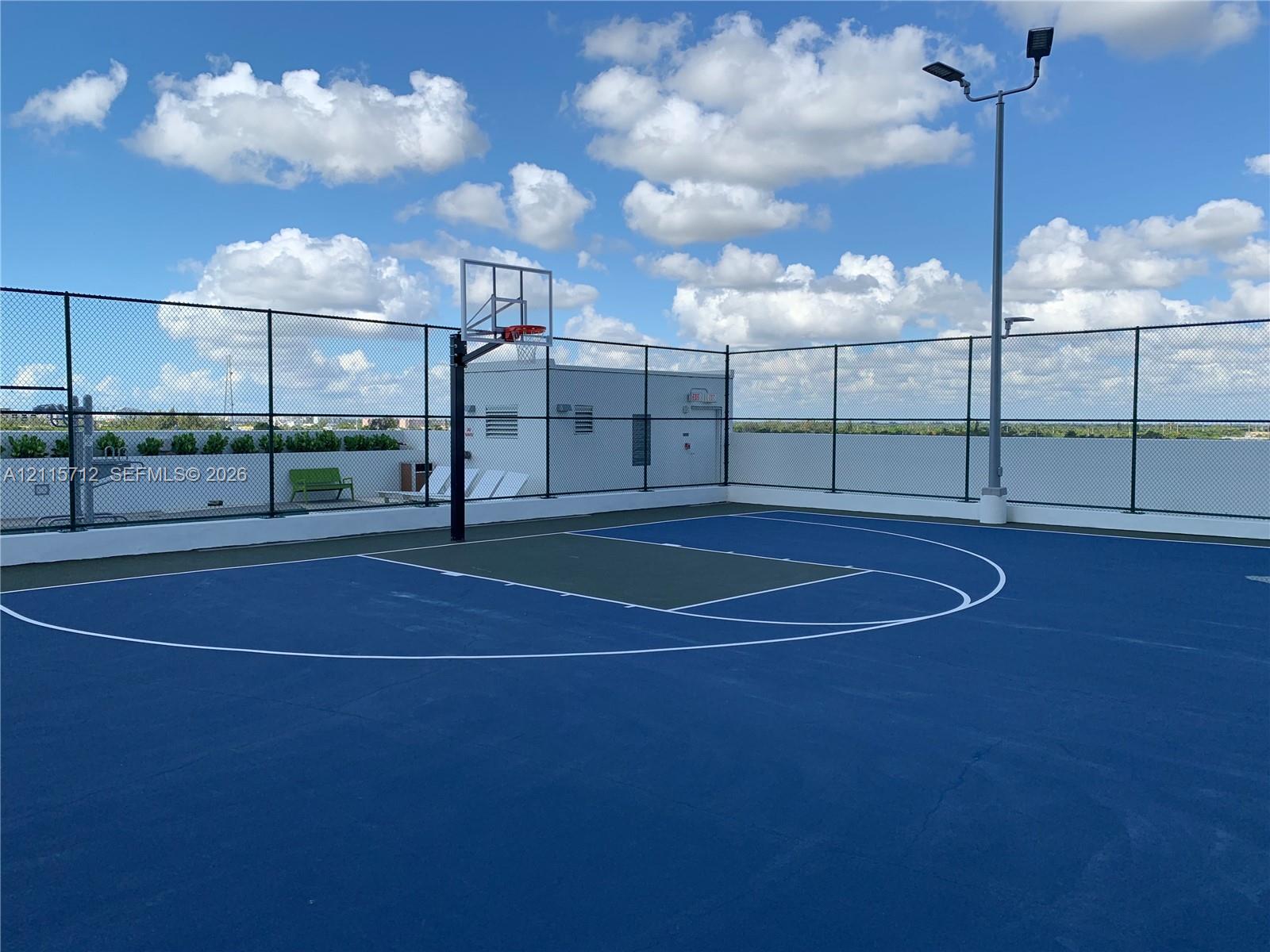 Rooftop basketball court featuring a high-performance surface, integrated lighting system, and full-perimeter chain-link fencing